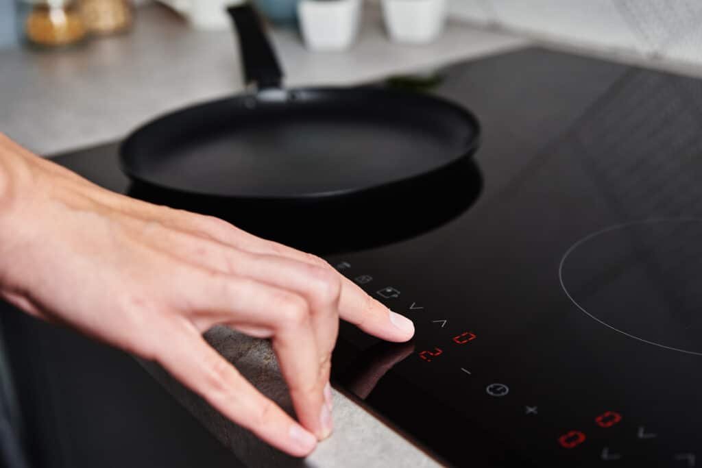 woman hand turns on modern induction stove in the 2022 12 16 12 46 40 utc
